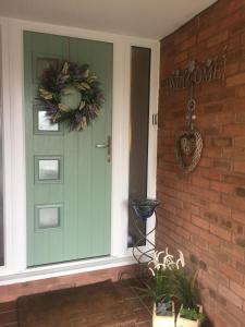 a green front door with a wreath on it at Wilmslow Airbnb in Wilmslow