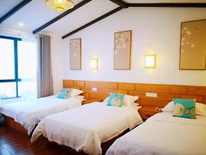 three beds in a room with white sheets and blue pillows at Zhangjiajie Tingyutang Little Yard in Zhangjiajie