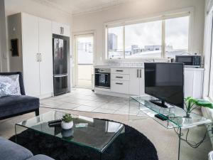 a living room with a tv and a glass table at U Suites on Manners in Wellington +38 photos
