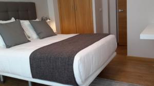 sypialnia z dużym łóżkiem z białymi prześcieradłami w obiekcie APARTAMENTOS PORTA NOVA w mieście Lugo