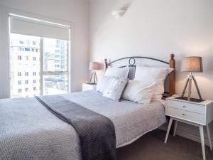 a bedroom with a bed with white pillows and a window at U Suites on Manners in Wellington
