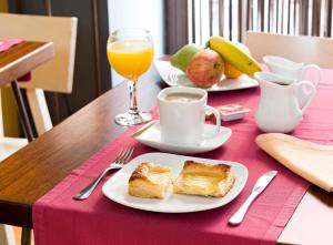 a table with two plates of bread and a cup of coffee at Hospedium Hotel Posada De La Luna in Huesca