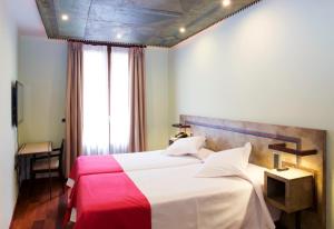 a bedroom with a large bed with a red and white blanket at Hospedium Hotel Posada De La Luna in Huesca