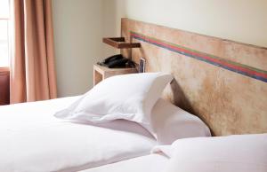 a bed with a white pillow on top of it at Hospedium Hotel Posada De La Luna in Huesca