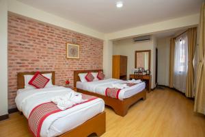 a hotel room with two beds and two windows at Kathmandu Boutique Hotel in Kathmandu