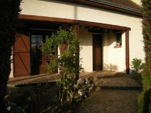 a porch of a house with a door and a plant at Au Nid de Tillé in Tillé