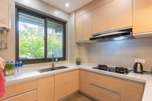 a kitchen with wooden cabinets and a sink and a window at 拈花湾景区内花园庭院别墅套房---购票入住 in Wuxi