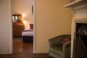 ein Zimmer mit einem Stuhl und ein Schlafzimmer mit einem Bett in der Unterkunft Hillview Heritage Estate in Sutton Forest