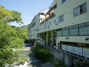 Itoen Hotel Bandai Mukaitaki في كورياما: مبنى بجانب نهر بجانب مبنى