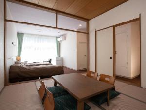 Itoen Hotel Bandai Mukaitaki في كورياما: غرفة بسرير وطاولة وغرفة نوم