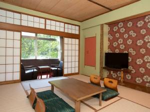 Itoen Hotel Bandai Mukaitaki في كورياما: غرفة بطاولة وكراسي وتلفزيون