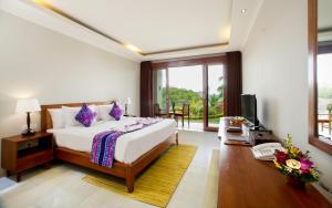 a bedroom with a bed and a television in it at Puri Pandawa Resort in Uluwatu