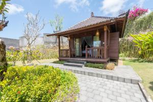a small cottage with a porch in a garden at Puri Pandawa Resort in Uluwatu