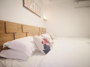 a white bed with white pillows and a wooden headboard at Zhangjiajie Tingyutang Little Yard in Zhangjiajie