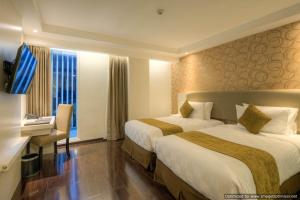 a hotel room with two beds and a desk at Platinum Adisucipto Hotel & Conference Center in Yogyakarta
