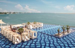 a group of chairs and tables on the beach at Royal M Hotel Abu Dhabi by Gewan in Abu Dhabi