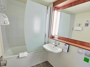 bagno con lavandino, doccia e specchio di Kyriad - Ecouen la Croix Verte a Écouen