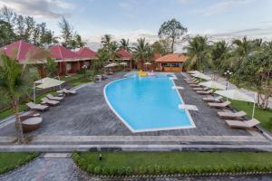 
a beach with a pool, chairs, and tables at Gold Coast Resort Phu Quoc in Phú Quốc
