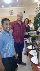 two men are standing next to a table with food at Hotel Sindha in Ruteng