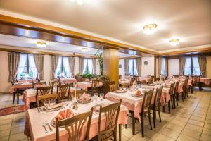 un comedor con mesas, sillas y ventanas en Hotel Le Postillon en Esch-sur-Sûre