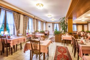 um restaurante com mesas, cadeiras e janelas em Hotel Le Postillon em Esch-sur-Sûre