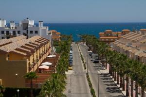 uma rua da cidade com palmeiras e edifícios e o oceano em Playamarina 1 Reception em Cabo Roig
