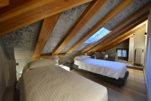 2 letti in una camera con soffitti in legno di Le Reve Charmant Apartments ad Aosta