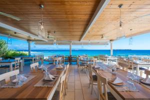 a restaurant with tables and chairs and a view of the ocean at Saint George Hotel in Chrissi Akti