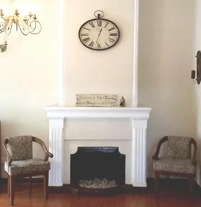 a clock on a wall above a fireplace with two chairs at Hotel Mount Pleasant in Bandarawela