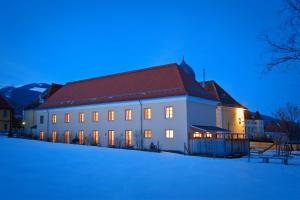 a large white building with a red roof in the snow at JUFA Hotel Seckau - Self Check-in in Seckau