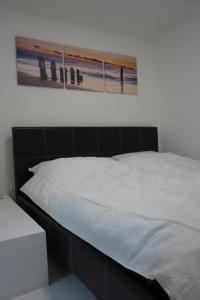 una cama blanca con una foto en la pared en Kastanienallee 7, en Hamburgo