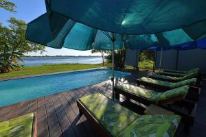 a patio with chairs and an umbrella and a swimming pool at Zambezi Mubala Lodge in Katima Mulilo