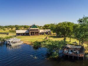 a building on a river with boats in the water at Chobe River Camp in Ngoma