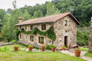 una casa de piedra con macetas delante de ella en El Molino de Rucandio, en Liérganes