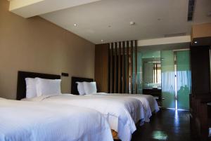 um quarto de hotel com duas camas com lençóis brancos em Century Hotel Taoyuan em Taoyuan