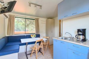 a kitchen with a blue couch and a table at Camping Residence Oliva in Rabac