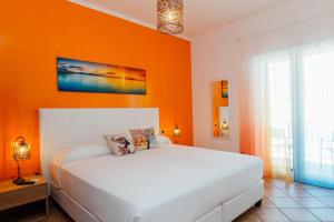 Vista Mare B&B في سورينتو: سرير أبيض في غرفة بجدار برتقالي