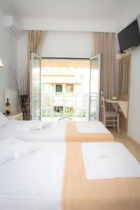 a bedroom with two beds and a large window at Hotel Astron in Myrina