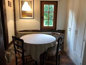 stół w pokoju z 2 krzesłami i oknem w obiekcie Maison Normande w mieście Auberville