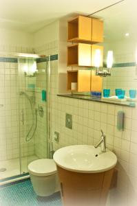 a bathroom with a sink and a shower and a toilet at Art Hotel Ahlen in Ahlen