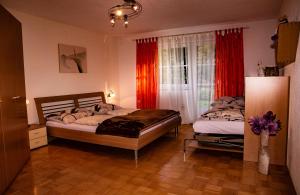 a bedroom with two beds and a window with red curtains at Haus Bitschnau in Wald am Arlberg