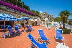 eine Gruppe blauer Stühle und Sonnenschirme auf einer Terrasse in der Unterkunft Residence Sant'Anna in Pietra Ligure