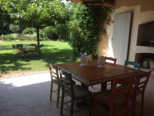 una mesa de madera y sillas en un patio en Les Amarines, en Saint-Rémy-de-Provence