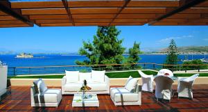 a patio with white furniture and a view of the water at Amphitryon Hotel in Nafplio