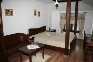 Oazis Guesthouse في Lovech: غرفة نوم بسرير واريكة وطاولة