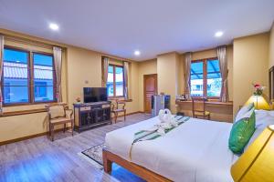 a hotel room with a bed and a television at Mina Garden Villa Resort in Chiang Mai