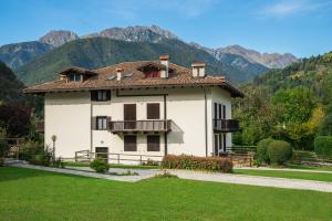 a large white house with mountains in the background at Appartamento Manuela in Pieve Di Ledro