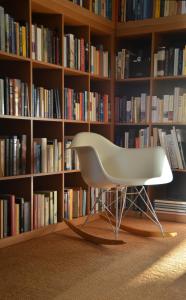 a white chair sitting in front of a book shelf at B&B Spoor62 in Gistel