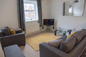 a living room with two couches and a television at The Robin Coach House by RentMyHouse in Hereford