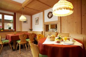 a dining room with two tables and chairs and a chandelier at Pension Epple in Oberjoch